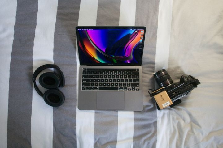 Travel Tech - a laptop computer sitting on top of a bed next to a camera