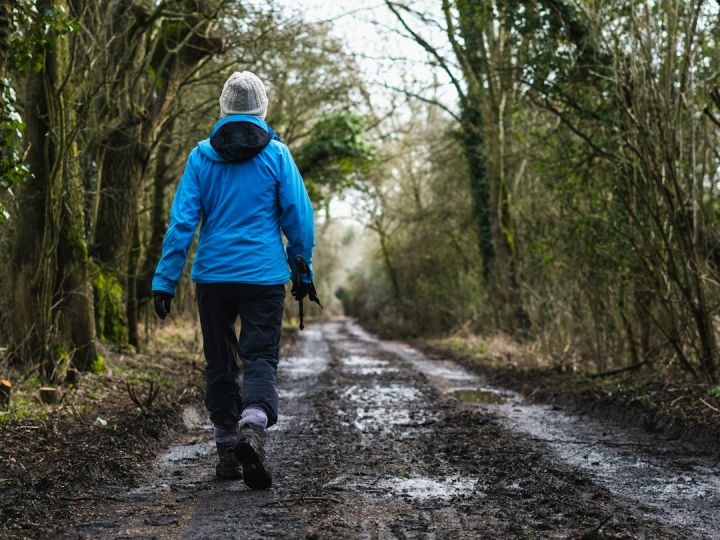 Waterproof - person in blue hoodie walking on dirt road during daytime