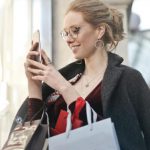 Shopping - Woman Standing Near Wall Holding Phone