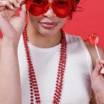 Gift Ideas - Woman in White Tank Top Holding a Red Heart Shaped Lollipop